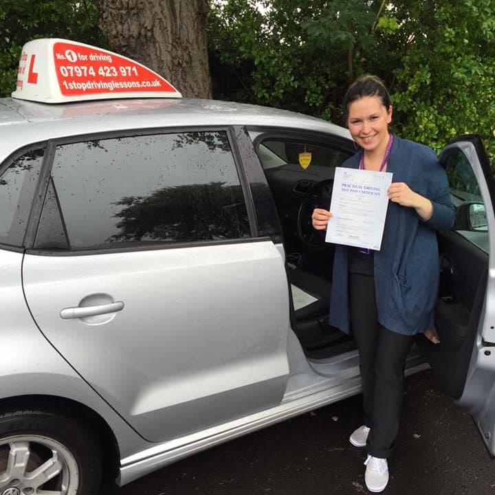 Newly passed learner holding their practical test pass certificate beside the One Stop School of Motoring car