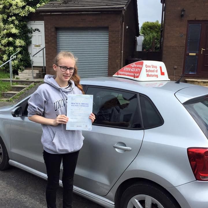 Newly passed learner holding their practical test pass certificate beside the One Stop School of Motoring car