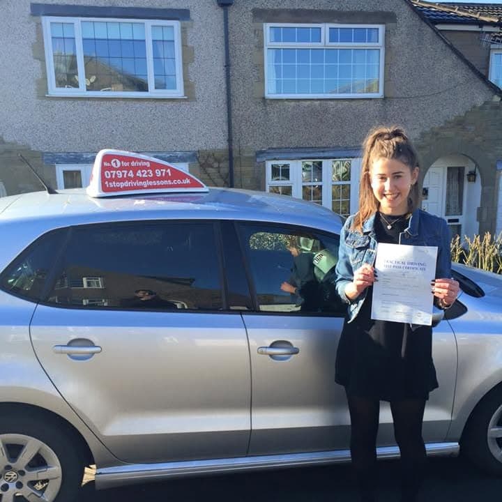 Newly passed learner holding their practical test pass certificate beside the One Stop School of Motoring car